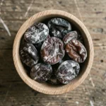 Pruneaux périmés dans un bol en bois présentant des traces de moisissures et une texture détériorée